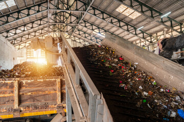 Close up of Conveyor belt transports garbage inside drum filter at recycling plant.