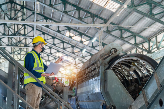A recycling plant engineer monitoring machine performance using advanced software on a sleek laptop in waste separation plant.