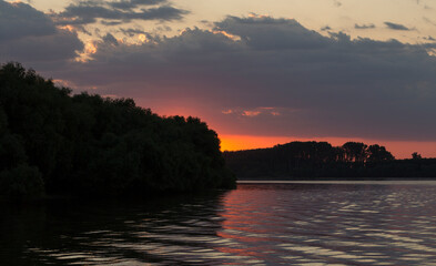 A bloody sunset on the Danube River. The reflection of the landscape in the water.