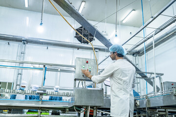 A factory technician inspects control panels in a modern food production facility, monitoring automated machinery to ensure efficiency, quality control, and adherence to food safety standards.
