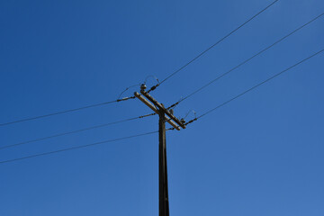 An electric pole of the power distribution network on a blue sky background