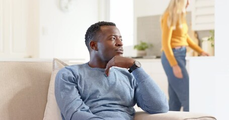 Thoughtful African American man sitting on couch at home, woman approaching