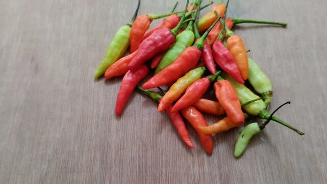 a bunch of cayenne pepper (cabe rawit) with a wooden texture background. This This cayenne pepper is famous for its very high level of spiciness.