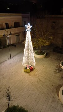 Riprese aeree della piazza di Teulada con l'albero di natale comunale ricco di regali. 