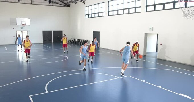 Basketball players in action on indoor court, competing with intensity and focus