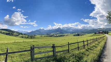 Valley landscape; road leads through field to mountains; a fence is near path. Used for travel brochures