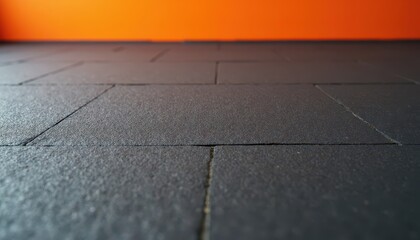 A textured asphalt floor with a bright orange wall for energetic product presentations.