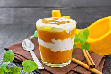 Dessert of pumpkin and yogurt in glass on dark wooden board