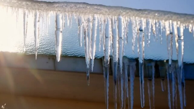 Slowly melting icicles on the roof, illuminated by the spring sun, creating an atmosphere of transition from winter to spring