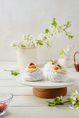 Step by step preparation of Easter nests from meringue with filling of fruit curd and butter cream on a light wooden background. Pavlova cake. Easter dishes.