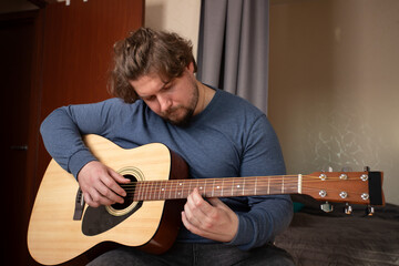 Obraz premium Man Practicing Acoustic Guitar, hobby and leisure activity, teaching musical skills, learning instrument.