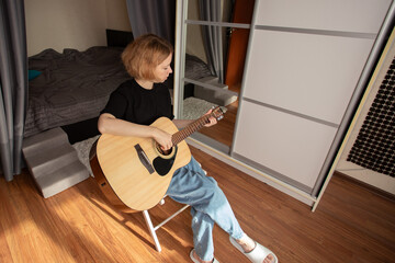 Woman Practicing Acoustic Guitar in Cozy Bedroom, musician enjoying string instrument practice,...