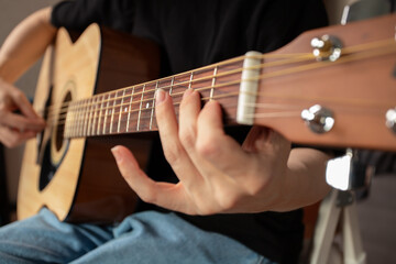 Fototapeta premium Hand Playing Acoustic Guitar Close-Up, concentration on fretboard, study of instrument, learning music