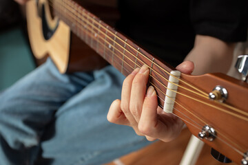 Fototapeta premium Hand Playing Acoustic Guitar Close-Up, performer practicing chords, strumming strings indoor