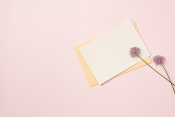 Paper blank sheet with flowers on pink background . Greeting card. Space for text. Flat lay, top view.