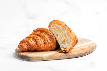 Croissants on wooden cutting board on white marble background