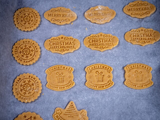 Cut out butter Christmas cookies before baking. Cookies are stored and baking paper so that they do not stick to the baking sheet.