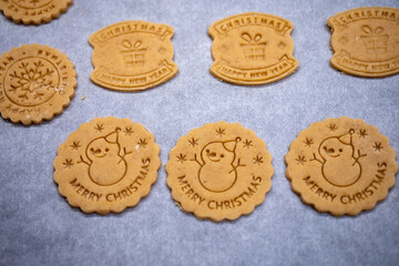 Cut out butter Christmas cookies before baking. Cookies are stored and baking paper so that they do not stick to the baking sheet.