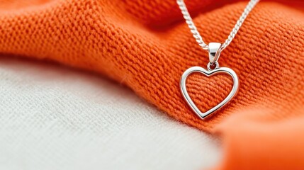 Valentine romance idea. Elegant silver heart pendant resting on vibrant orange fabric, symbolizing love.