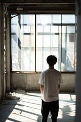 Young Person Standing in Sunlit Abandoned Room with Shadows