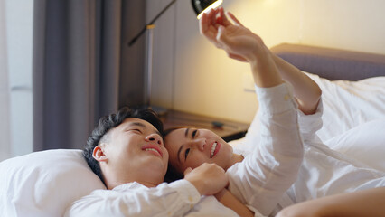 Top view young couple asia people lying down talk on bed relax smile hold hands look at ring on...