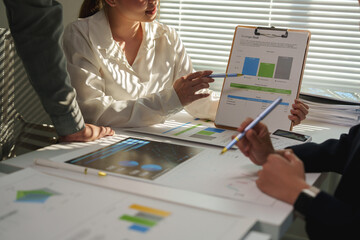 Business professionals analyzing financial charts and graphs that highlight market growth while utilizing digital tablets during a collaborative meeting in a corporate office setting