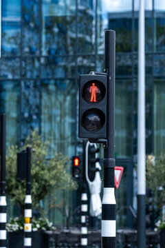 This image captures a red pedestrian signal featuring a simplified figure, set against a minimalist backdrop, emphasizing urban life and safety in Amsterdam