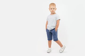 Caucasian cute boy of 4 years old model looks expressively and poses in a T-shirt, shorts and...