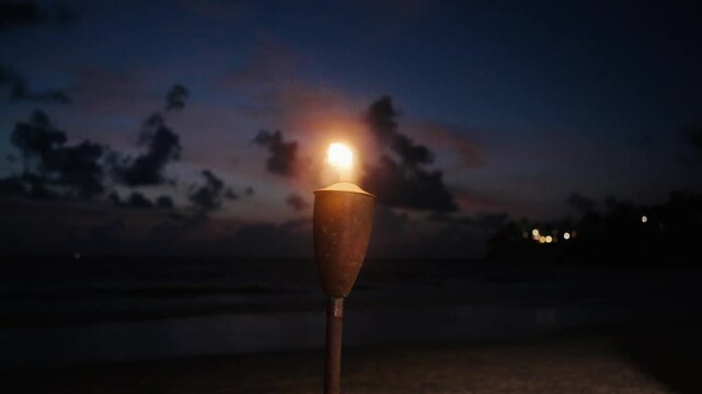 Tiki Lantern Flame Torch on beach,island on warm summer night waving on ocean breeze.summer background