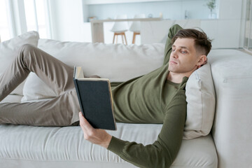 Man is reading a book on a couch