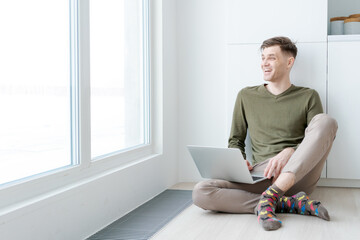 Man is sitting on the floor with a laptop in front of him