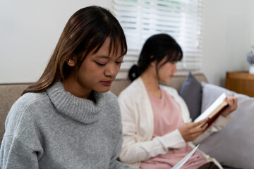 Female higher education student using laptop and studying book in home, Online learning.