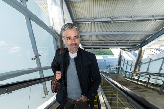 Stylish commuter ascending escalator in modern transport station