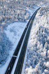 Highway between snow covered forest in the mountains