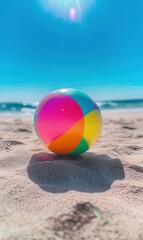 Obraz premium Colorful beach ball on sandy shore, ocean waves in background, summer fun concept.