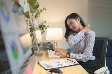 Young office worker massaging her neck to relieve discomfort from prolonged computer use, experiencing symptoms of office syndrome and highlighting the importance of ergonomic practices