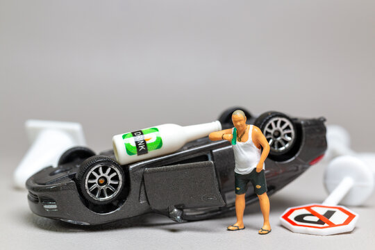 A Drunk driver holding a liquor bottle as he steps out of a car. concepts of reckless behavior, urban life