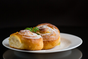 Baked goods. Sweet buns with cottage cheese filling and honey in a plate isolated on a black background