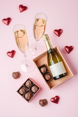 Glasses of champagne, champagne bottle and praline gift box. Surrounded by heart shaped chocolates. Isolated on pink background. Valentine's day, Greetings, Valentine, Gift, Surprise.