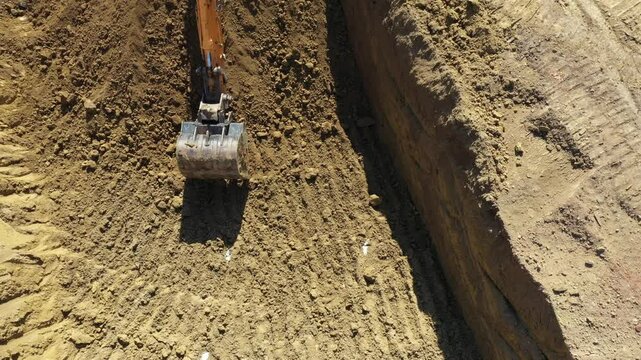 Above top dolly move view on two big excavators as they digging, excavating foundation for new residential building and filling few dumper trucks with soil, ground at construction site.