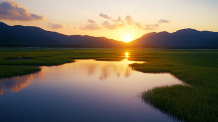 Fototapeta premium A picturesque sunset over peaceful wetlands with grassy patches and distant hills, reflecting warm sunlight on tranquil water, evoking serenity and natural beauty.