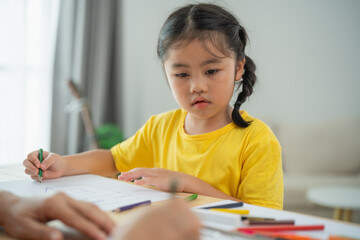 Focused Young Girl Engaged in Creative Drawing Activity at Home, With Arts and Crafts Supplies Spread Across the Table, Emphasizing Childhood Imagination and Engagement in Learning