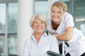 Obraz premium happy nurse taking care of a senior woman in wheelchair