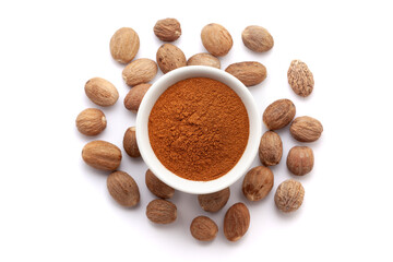 A bowl of Organic Nutmeg (Myristica fragrans) powder, placed over a heap of whole nutmegs. Isolated on a white background.