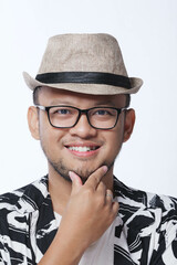 Close up picture of a cheerful young Asian man smiling wearing hat and glasses.