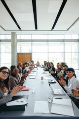 Group of people clapping around conference table in modern office space