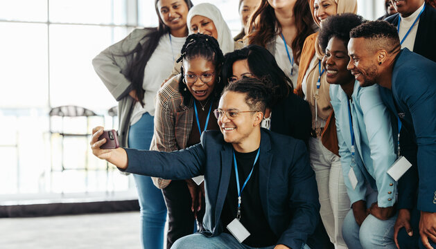 Business people taking a cheerful selfie after a workshop to celebrate collaboration and teamwork in a diverse and inclusive environment
