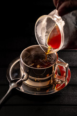 Pour coffee into a stainless steel cup using a glass pot