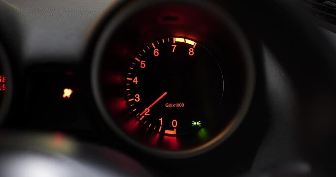 Illuminated car rev counter gauge close up shot. Engine being revved, real time, no people, real sound