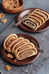 Bejgli, home-baked roll, traditional Hungarian, Eastern European Christmas and Easter sweet bread in slices stuffed with ground walnuts and poppy seed filling on a gray background